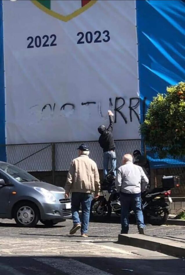 Tifosi della Turris intenti a rimuovere la scritta dalla bandiera del Napoli a Torre del Greco