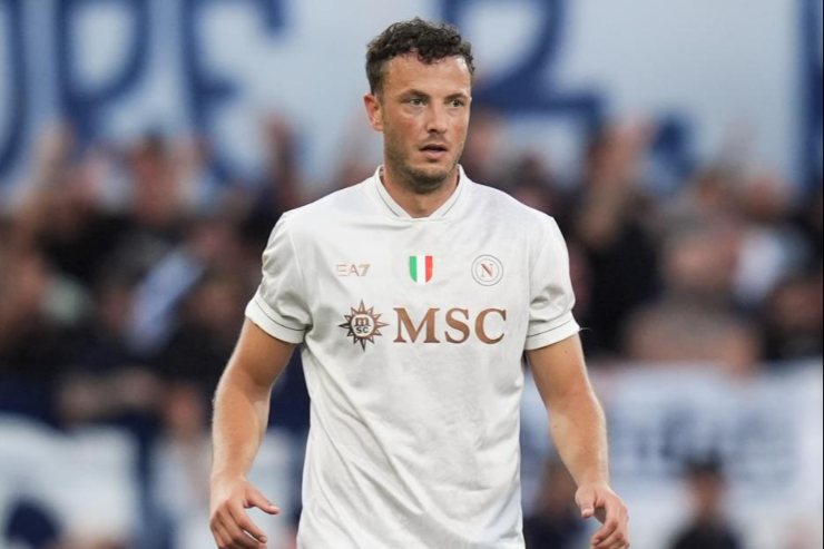 Amir Rrahmani del Napoli in azione durante una partita, mentre controlla il pallone con la maglia bianca del club, concentrato sul gioco.