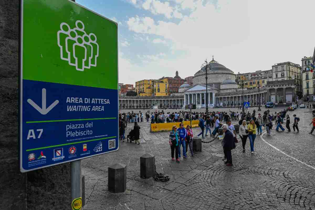 Cartello di area di attesa in Piazza del Plebiscito a Napoli, con cittadini riuniti dopo il terremoto del 2025.