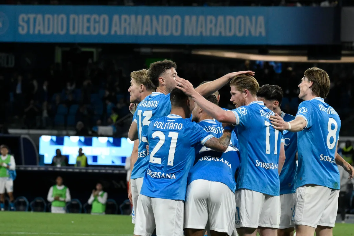 Giocatori del Napoli in cerchio nello stadio Diego Armando Maradona, con maglietta blu e pantaloncini bianchi durante una partita