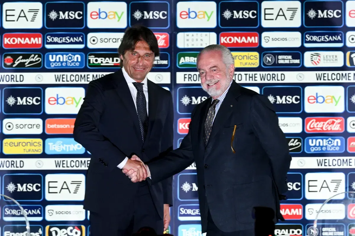 Aurelio De Laurentiis e Antonio Conte si stringono la mano in conferenza stampa con i banner degli sponsor del Napoli sullo sfondo