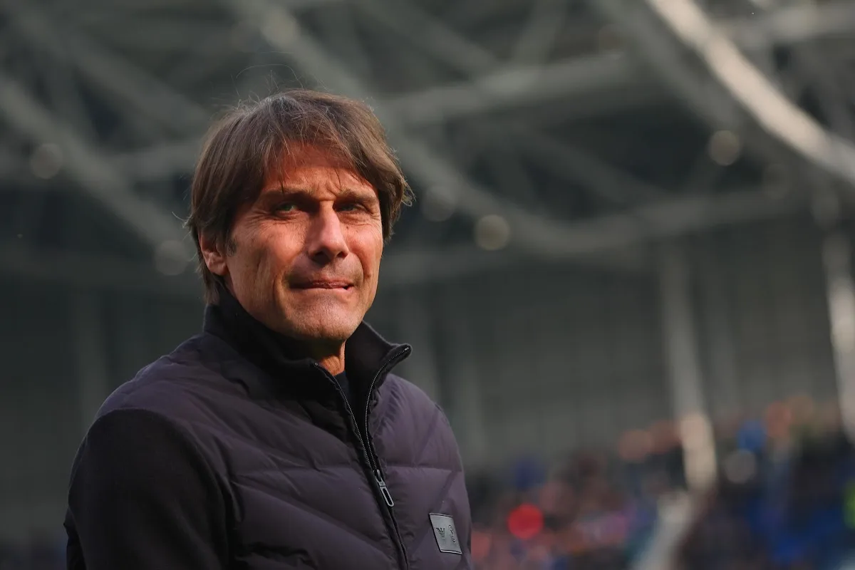 Antonio Conte in panchina, ritratto durante una partita del Napoli con giubbotto nero da allenatore