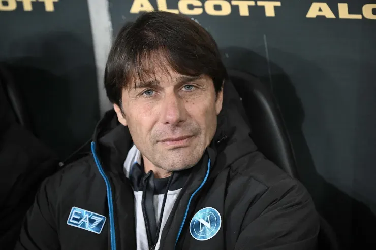 Antonio Conte in panchina durante una partita, con abbigliamento tecnico nero e blu
