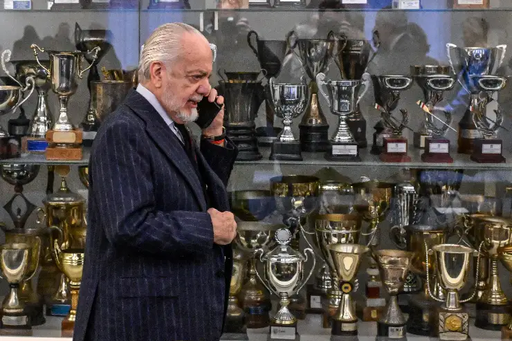 Aurelio De Laurentiis al telefono davanti a una bacheca di trofei