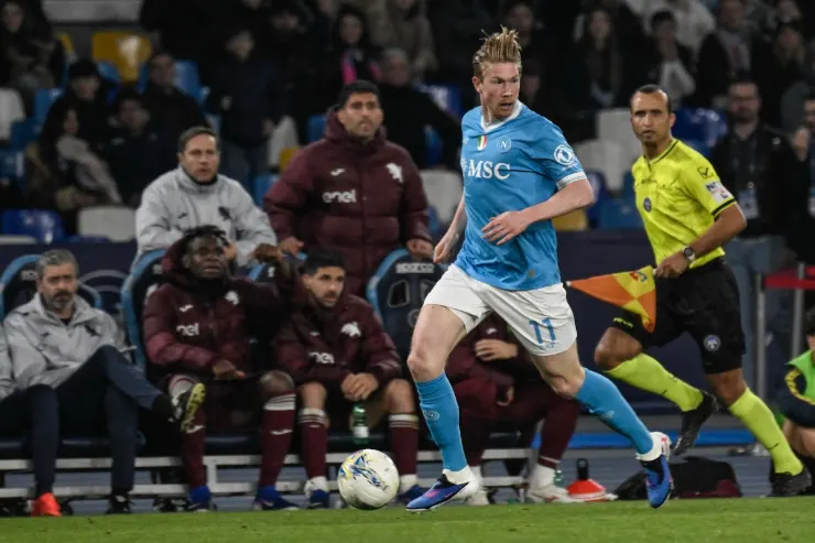 De Bruyne con maglia azzurra Napoli in azione durante una partita, palla al piede davanti alla panchina avversaria