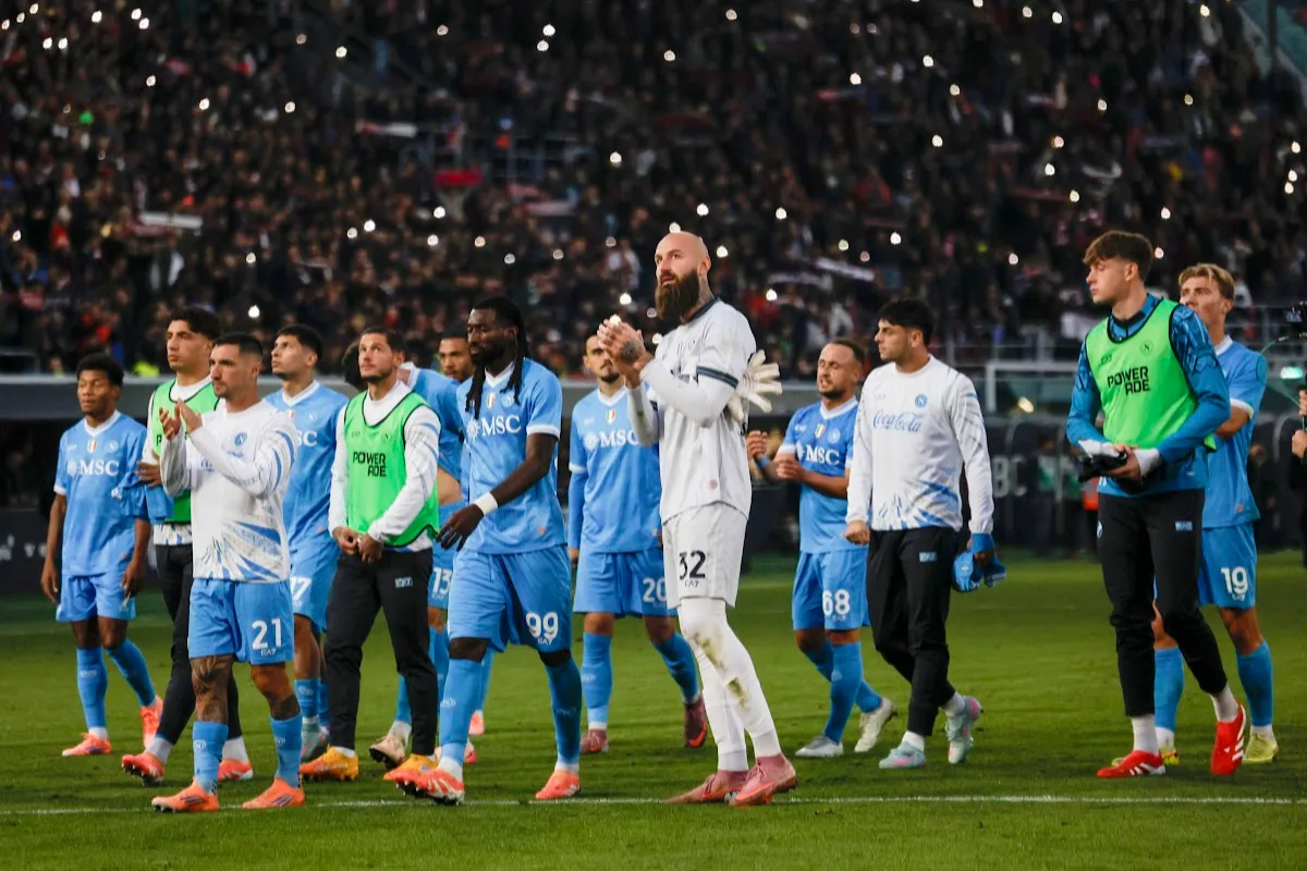 Squadra del Napoli in campo dopo la partita, giocatori in divisa blu e bianca con stadio illuminato sullo sfondo
