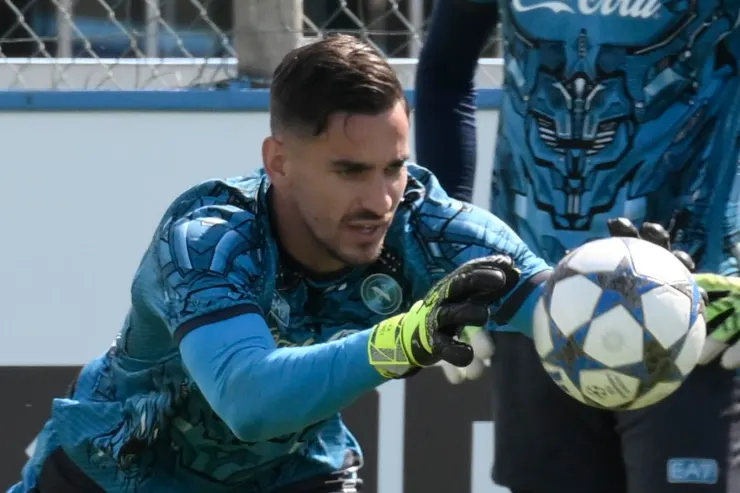 Alex Meret in blue SSC Napoli goalkeeper kit makes a diving save with a football during training