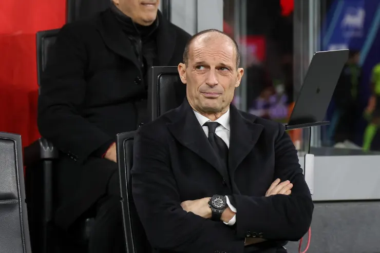Massimiliano Allegri in panchina con le braccia incrociate, indossa abito nero e cravatta