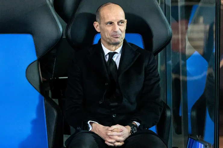 Massimiliano Allegri seduto in panchina con abito nero e cravatta durante una partita