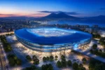 Stadio Diego Armando Maradona di Napoli illuminato al tramonto con il Vesuvio sullo sfondo e la baia della città