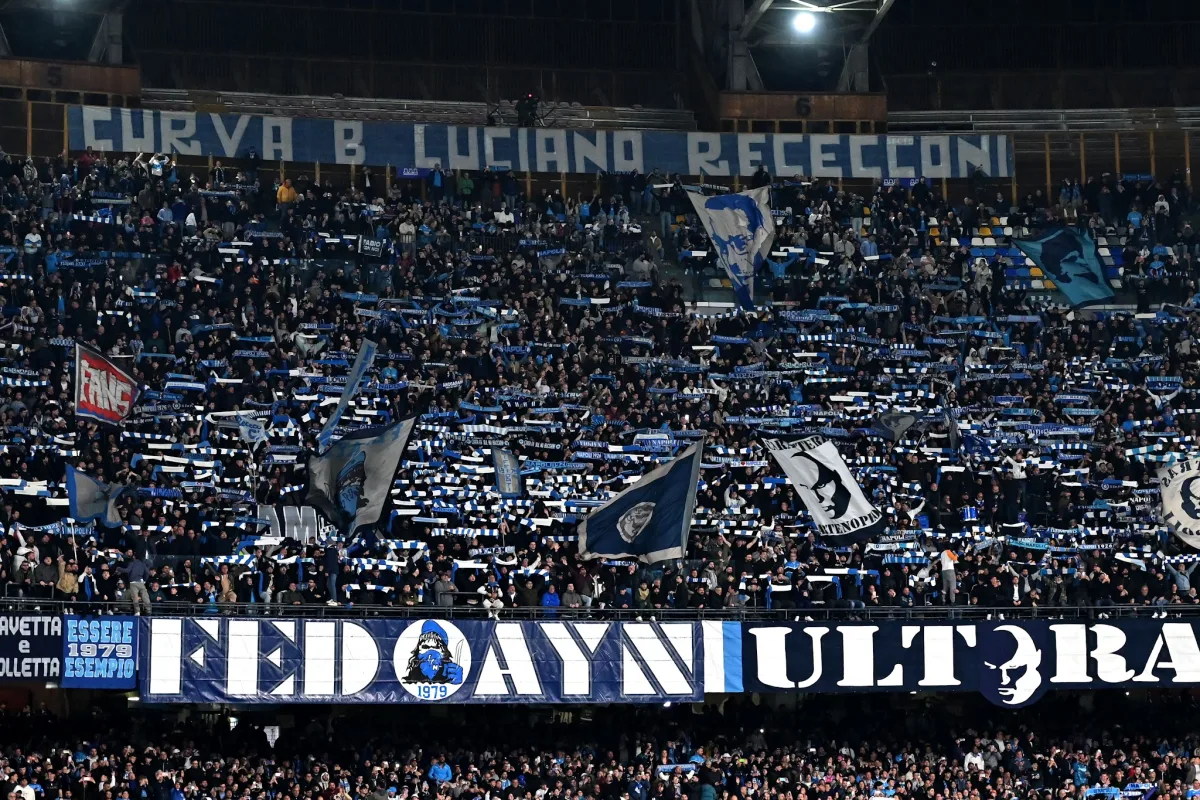 Curva B dello stadio San Paolo di Napoli con tifosi che espongono striscioni e bandiere blu e bianche