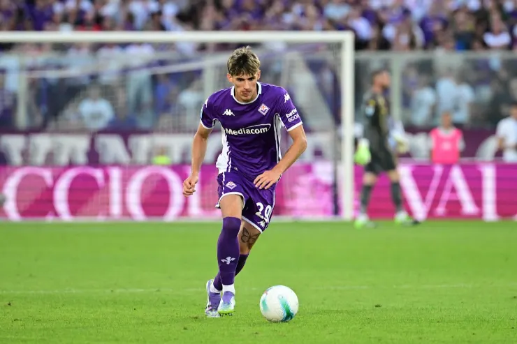 Fortini in azione con il pallone durante una partita, indossa la maglia viola della Fiorentina