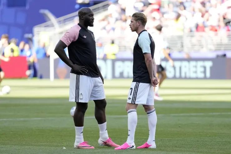 Lukaku e De Bruyne conversano in campo durante una partita di calcio in uno stadio affollato