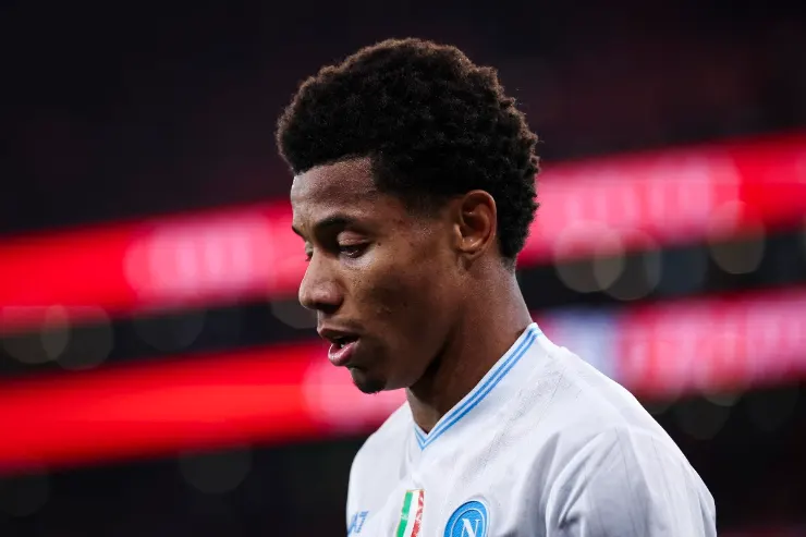 David Neres in maglia Napoli durante una partita, con lo sfondo dello stadio illuminato