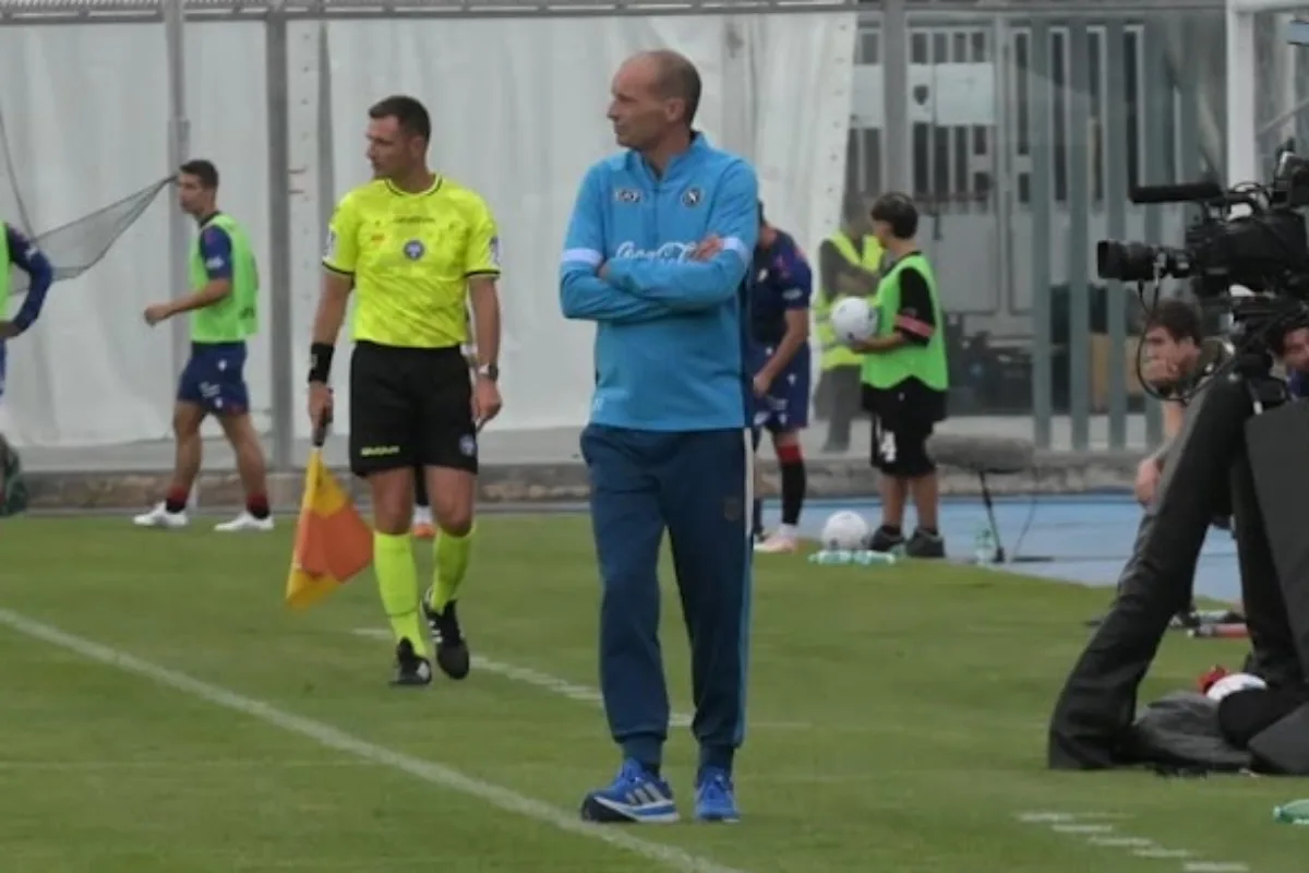 Allenatore in tuta azzurra Napoli osserva l'allenamento durante il ritiro precampionato con staff e telecamera a bordo campo
