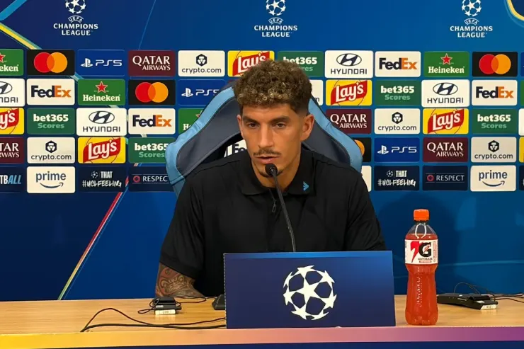 Giovanni Di Lorenzo in conferenza stampa prima di Napoli-Arsenal, seduto al tavolo con microfono davanti allo sfondo Champions League