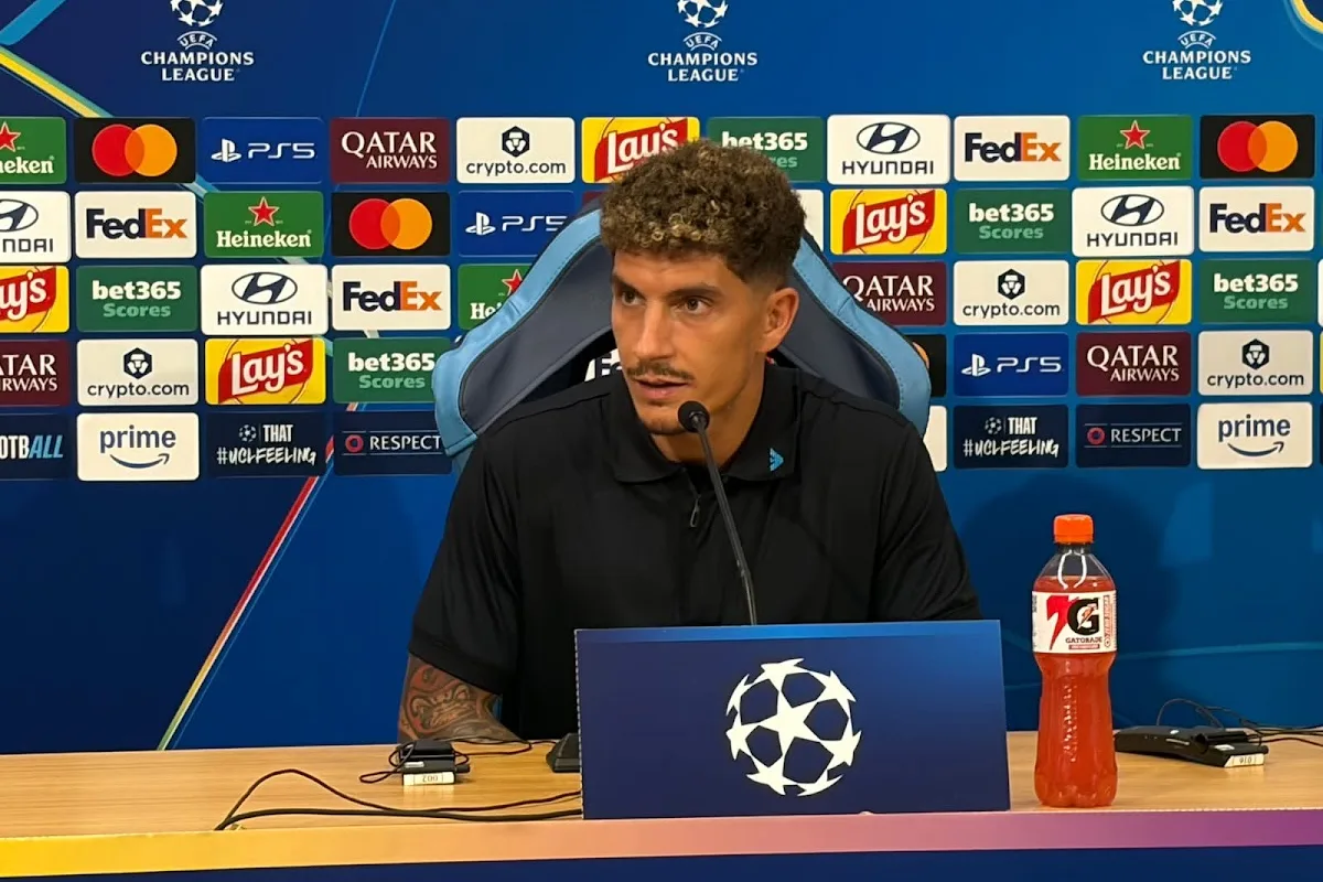 Giovanni Di Lorenzo durante la conferenza stampa Champions League, seduto al tavolo con microfono davanti al backdrop ufficiale