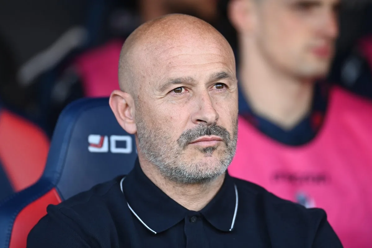 Vincenzo Italiano in panchina durante una partita, seduto in abbigliamento tecnico nero con espressione concentrata