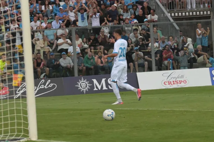 Lucca in azione durante una partita di calcio, con il pallone in primo piano e i tifosi sullo sfondo