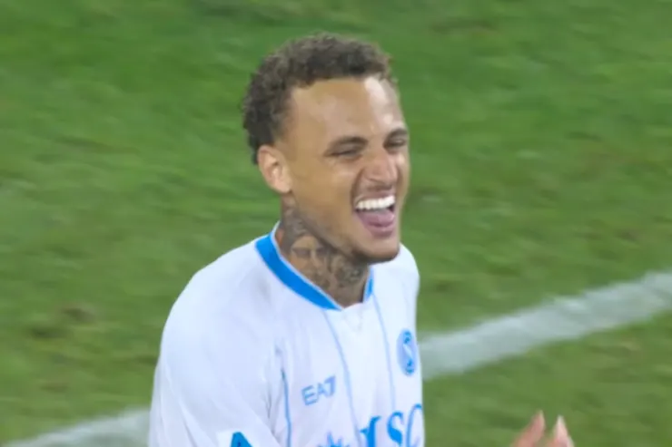 Noa Lang sorride durante una partita del Napoli, indossa la maglia bianca con dettagli blu