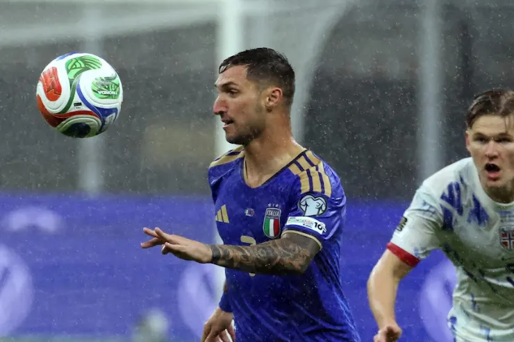 Matteo Politano in nazionale italiana controlla il pallone sotto la pioggia durante una partita