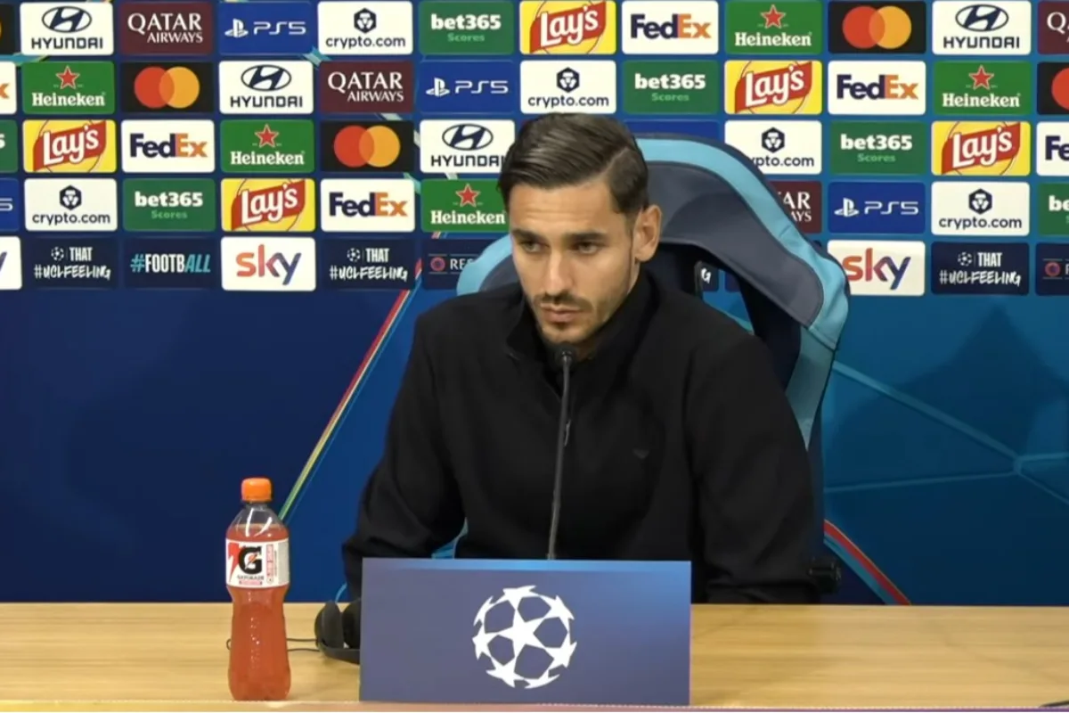 Conferenza stampa Champions League con un giocatore del Napoli in maglia nera davanti ai loghi sponsor