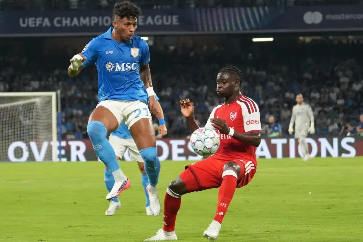 Alisson Santos in maglia Napoli azzurra contrasta con un giocatore dell'Arsenal in rosso durante una partita di UEFA Champions League