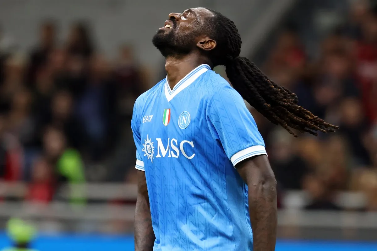 Calciatore del Napoli con maglia azzurra con sponsor MSC e dreadlock, testa alzata ed espressione delusa durante una partita