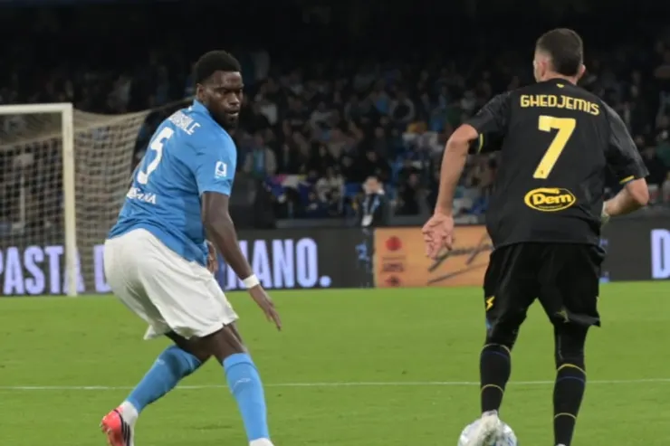 Difensore del Napoli in maglia azzurra contrasta avversario in maglia nera durante partita di calcio