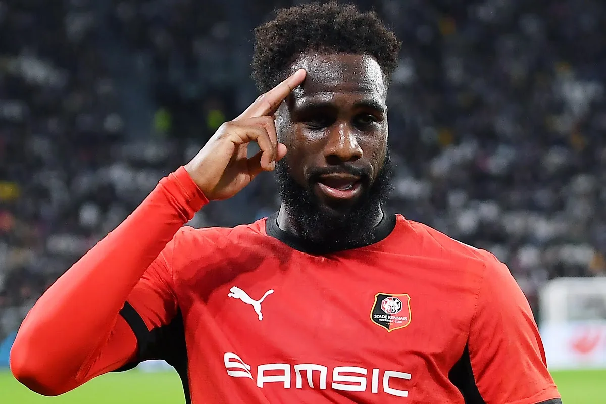 Calciatore con maglia rossa dello Stade Rennais che si tocca la tempia durante una partita