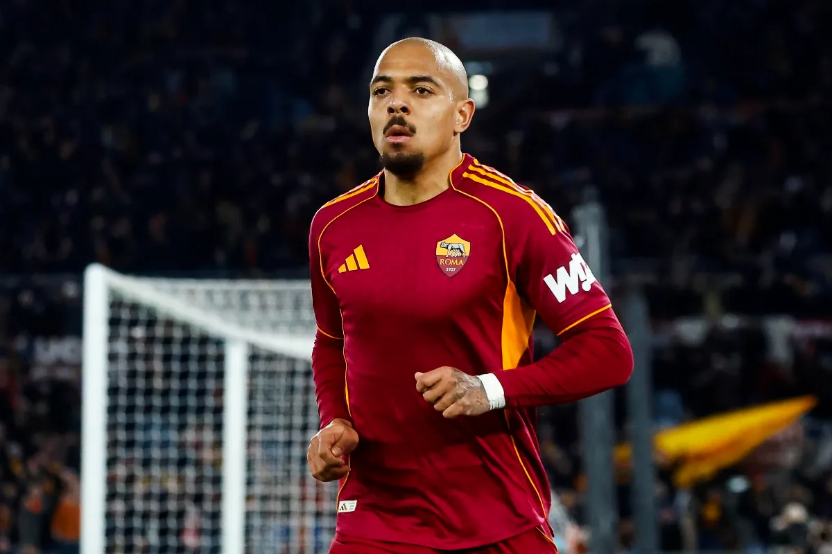 Malen con la maglia rossa della AS Roma e lo stemma sul petto, in primo piano allo stadio con tifosi sullo sfondo