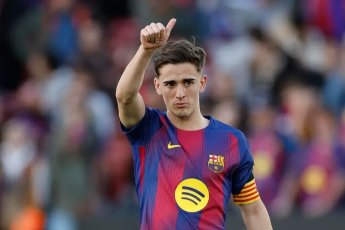 Calciatore con maglia blaugrana del Barcellona, fascia da capitano al braccio e pollice alzato davanti al pubblico sfocato