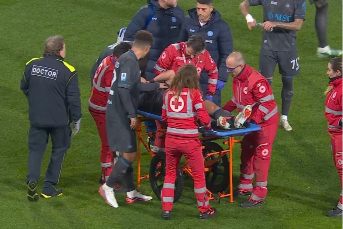 Calciatore del Napoli steso sulla barella portata via dal campo dai sanitari della Croce Rossa, con medico e staff intorno
