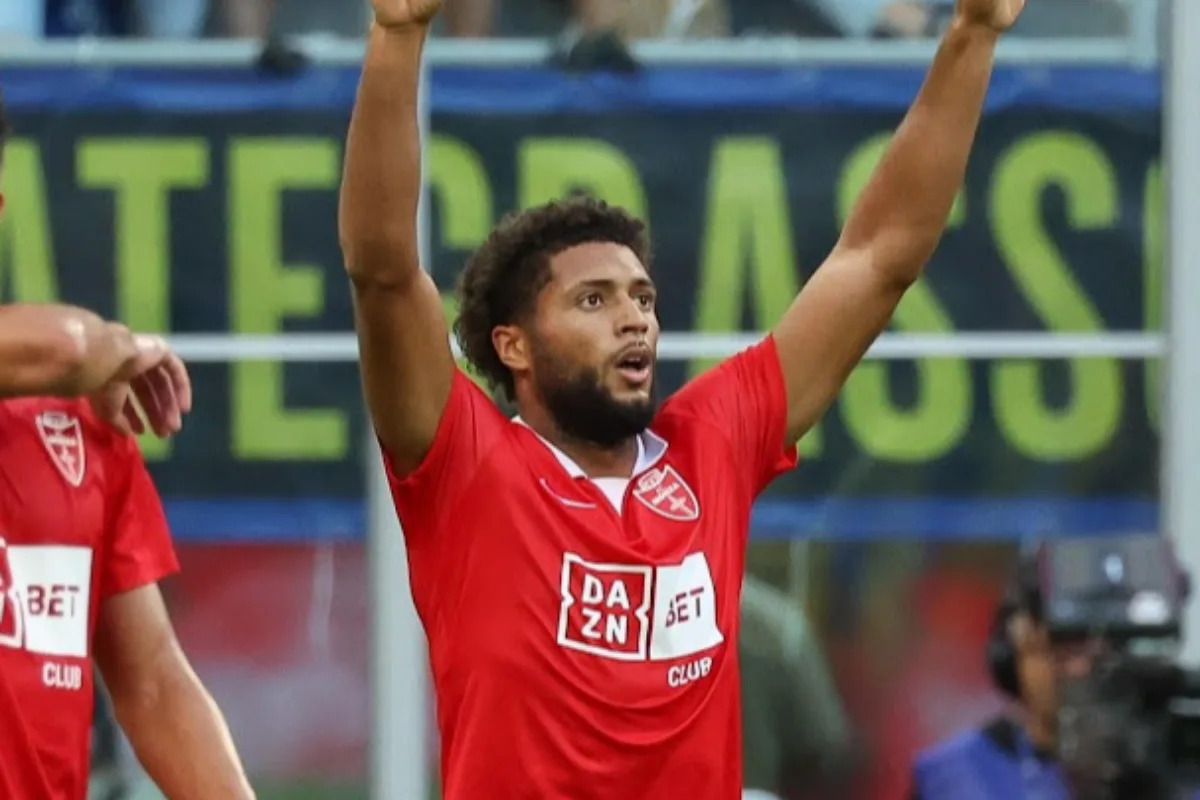 Calciatore con maglia rossa del Monza con sponsor DAZN e BET, braccia alzate in esultanza durante una partita