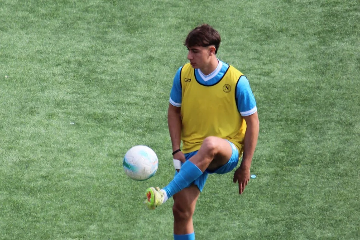 Giovane calciatore in maglia gialla e blu durante l'allenamento su campo in erba sintetica