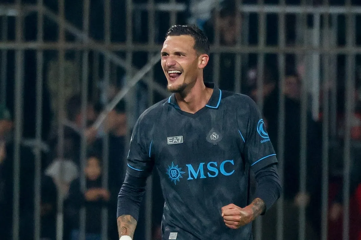 Calciatore del Napoli con maglia scura sorride ed esulta a pugno chiuso, con sponsor MSC sul petto